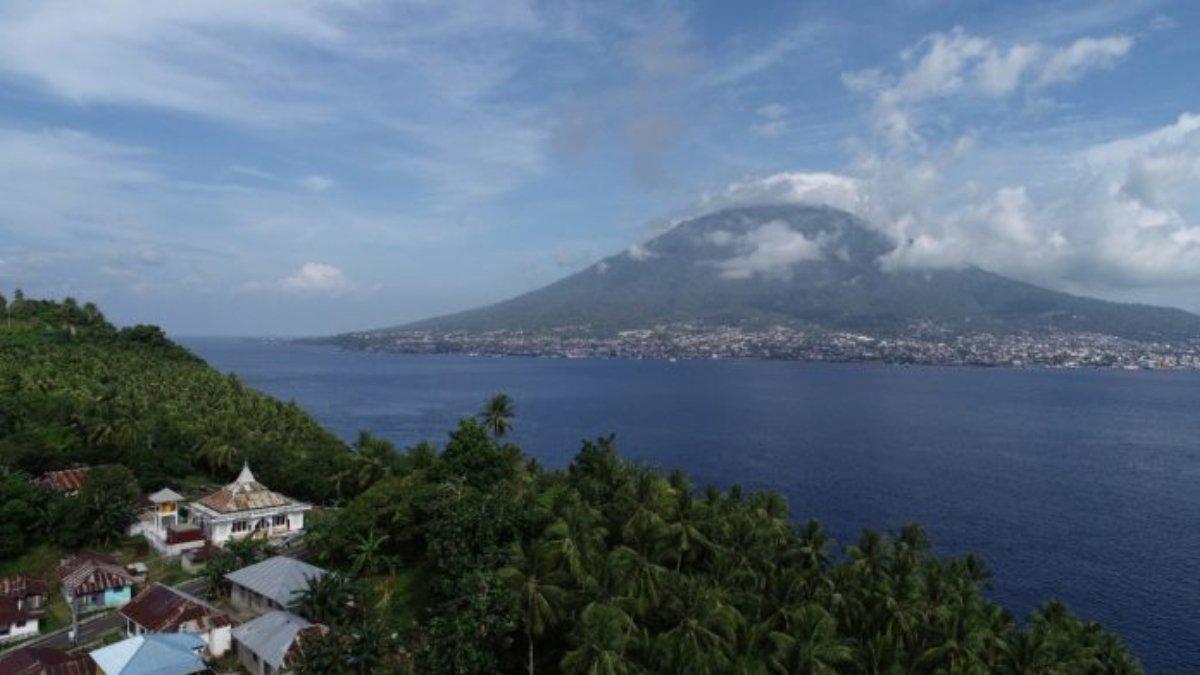Pulau Ternate dilihat dari Pulau Tidore. Reruntuhan Benteng Cobo tertutup pepohonan di sebelah kanan masjid.