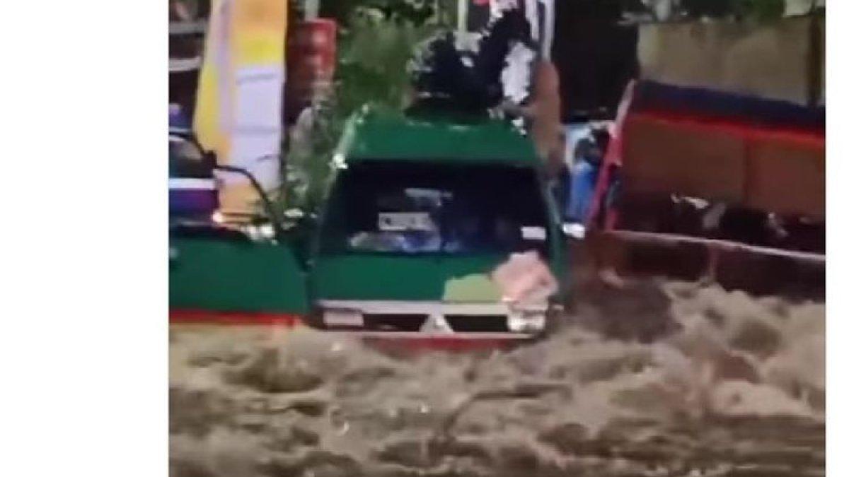 Sebuah angkutan kota (angkot) berwarna hijau terjebak banjir luapan Sungai Ciputri di Jalan Mahar Martanegara, Kota Cimahi, Jawa Barat, Selasa (5/12/2023) malam.