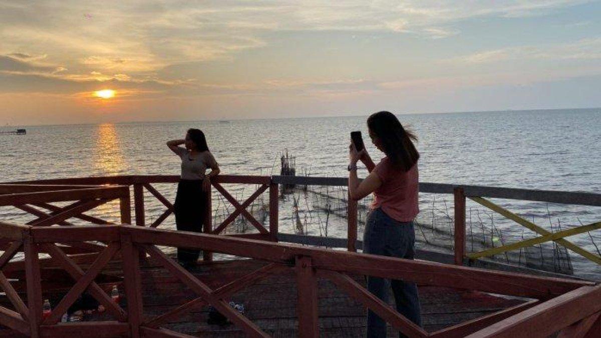WISATA MAKASSAR – Wisatawan menikmati kawasan Mangrove Lantebung, Makassar, Minggu (13/4/2025). Daya tarik utama wisata ini adalah pemandangan sunset.
