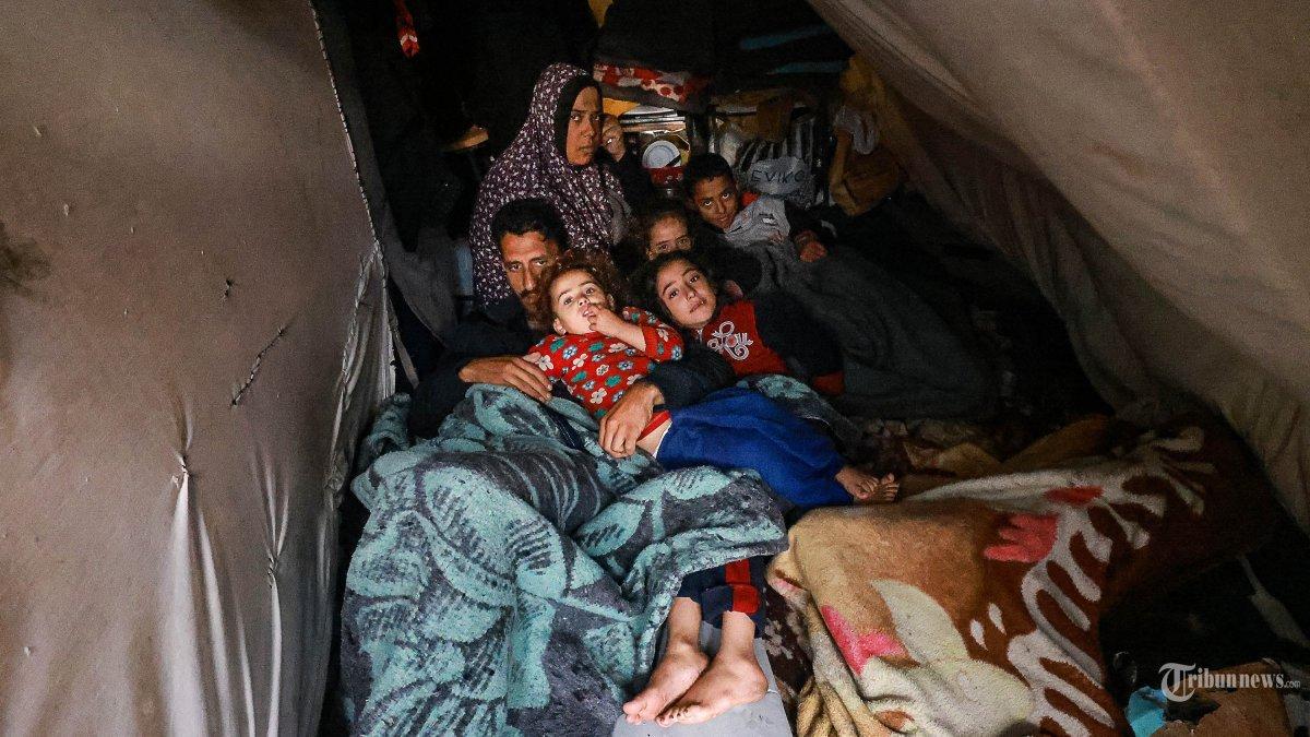 Warga Palestina beristirahat di tenda darurat mereka di sebuah kamp yang didirikan di halaman sekolah di Rafah di Jalur Gaza selatan tempat sebagian besar warga sipil mengungsi, pada 13 Desember 2023, ketika pertempuran terus berlanjut antara Israel dan kelompok militan Palestina Hamas.