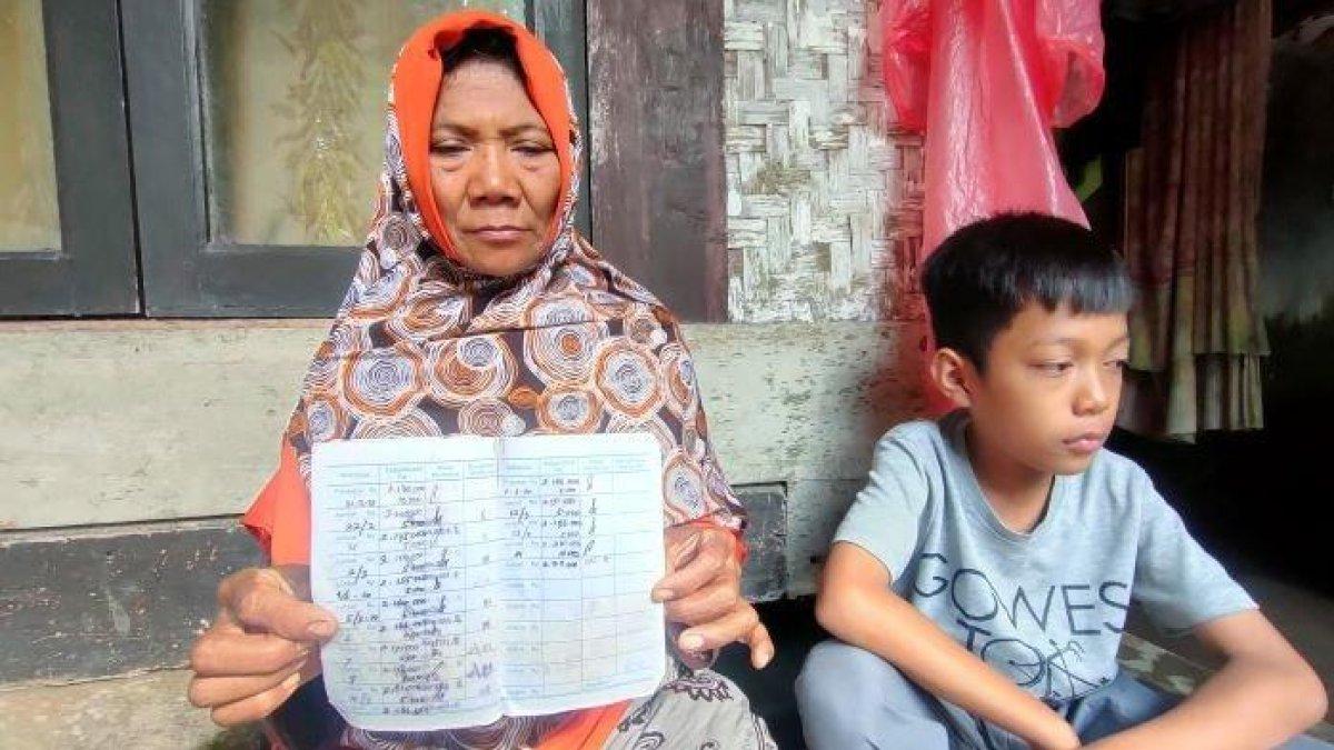 Armilah bersama anaknya memperlihatkan buku tabungan yang belum dikembalikan pihak sekolah di Pangandaran, Jumat (30/6/2023).