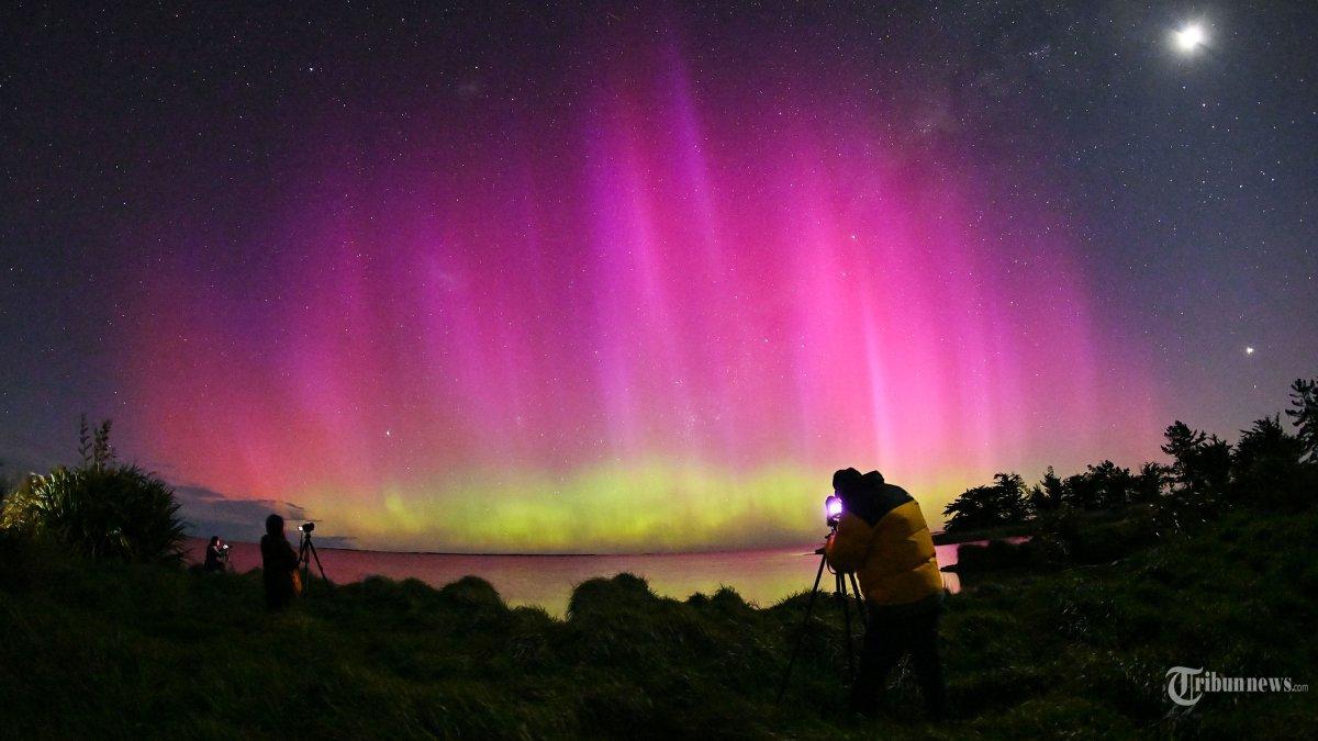 SOAL OSN GEOGRAFI - Orang-orang mengambil gambar Aurora Australis, juga dikenal sebagai Cahaya Selatan, saat bersinar di cakrawala di atas perairan Danau Ellesmere di pinggiran Christchurch pada 8 Oktober 2024. (ARSIP, 2024)