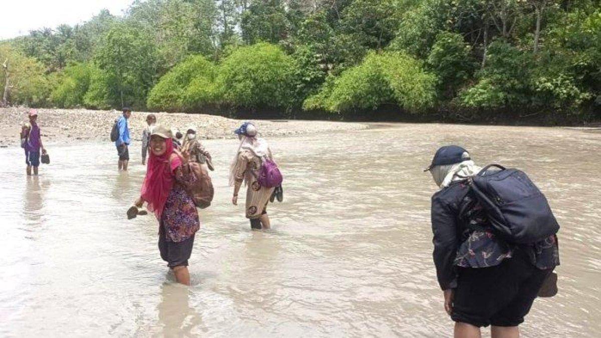 guru sedang melewati sungai untuk bisa tiba di Desa Tanjung Raman, Bengkulu