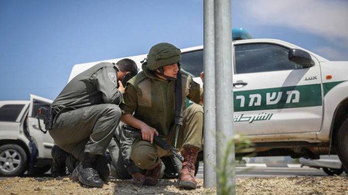 BERLINDUNG - Pasukan Israel (IDF) tampak berlindung di pinggir jalan raya