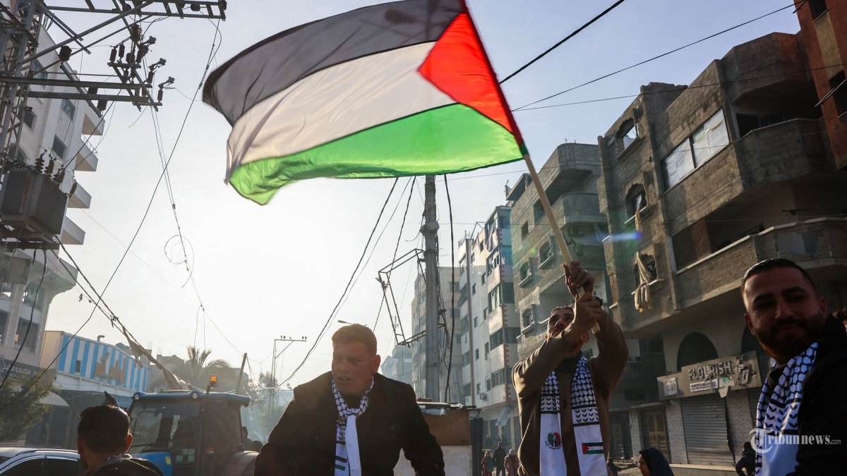 Seorang pria mengibarkan bendera Palestina saat orang-orang merayakan kesepakatan gencatan senjata dalam perang Israel-Hamas di Kota Gaza pada 19 Januari 2025. Gencatan senjata yang telah lama ditunggu-tunggu dalam perang Israel-Hamas ditunda pada 19 Januari setelah Perdana Menteri Benjamin Netanyahu mengatakan pada pertemuan tersebut. pada menit terakhir bahwa hal itu tidak akan berlaku sampai kelompok militan Palestina memberikan daftar sandera yang akan dibebaskan. (Photo by Omar AL-QATTAA / AFP)