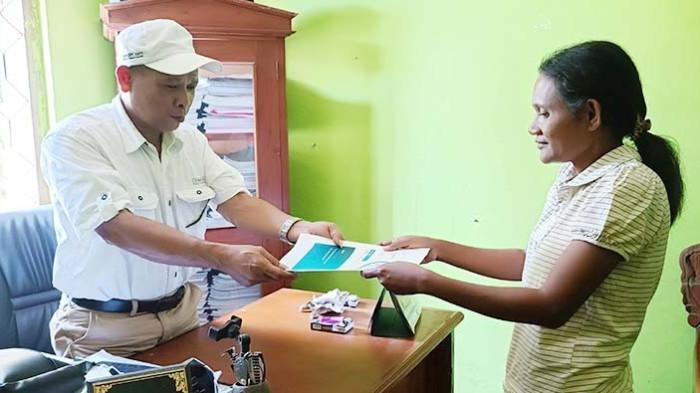 TERIMA LAPORAN - Kepala Desa Geliting Makarius Oskar (58) sedang menerima laporan perkembangan agen Pesiar Maria Nona Erni (39) di Kantor Desa Geliting di Kecamatan Kewapante, Sikka, Flores, Nusa Tenggara Timur, Jumat 25 Juli 2025. Pemdes apresiasi kehadiran agen Pesiar BPJS Kesehatan.