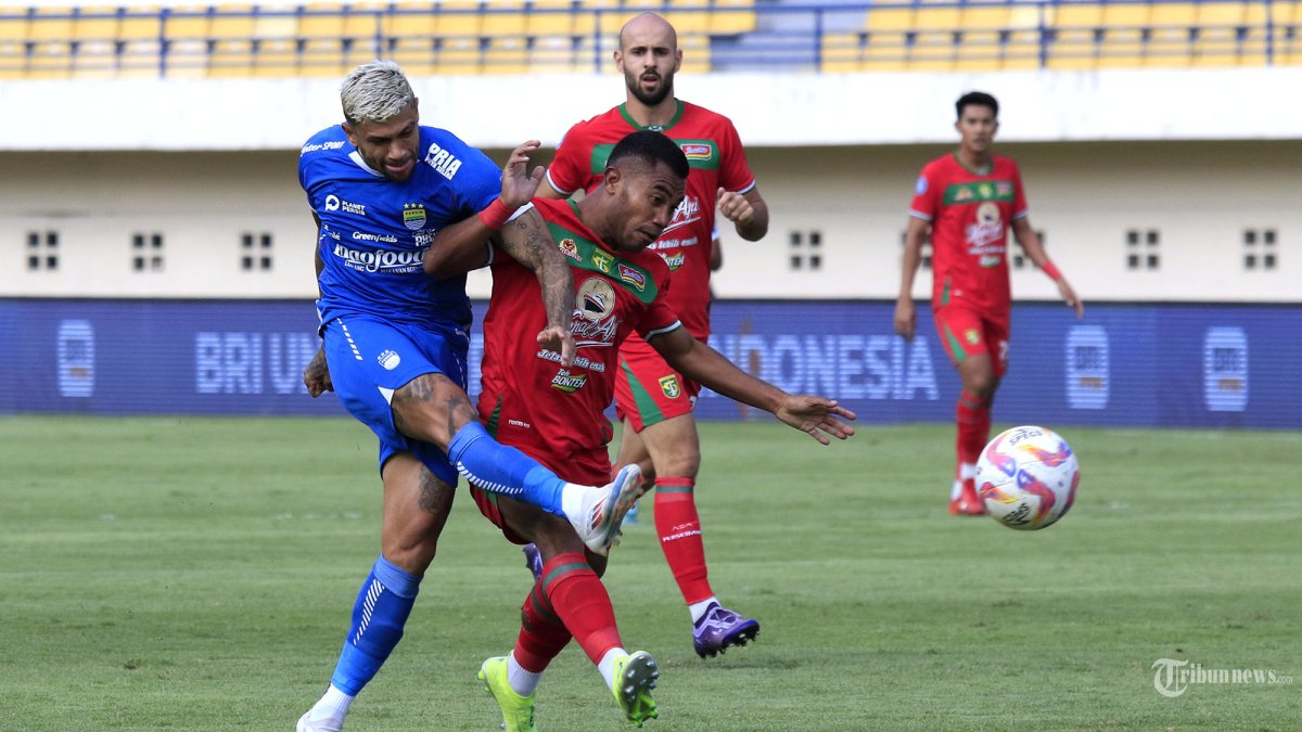 Pemain Persib Bandung, Ciro Alves berusaha melancarkan tendangan bola ke gawang dibayang-bayangi pemain Persebaya Surabaya, Ardi Idrus pada lanjutan Liga 1 2024-2025 di Stadion Si Jalak Harupat, Kabupaten Bandung, Jawa Barat, Jumat (18/10/2024). Pertandingan yang digelar tanpa penonton tersebut dimenangkan Persib dengan skor 2-0 lewat gol yang dicetak Edo Febriansah menit ke-22 dan Ciro Alves menit ke-71. TRIBUN JABAR/GANI KURNIAWAN