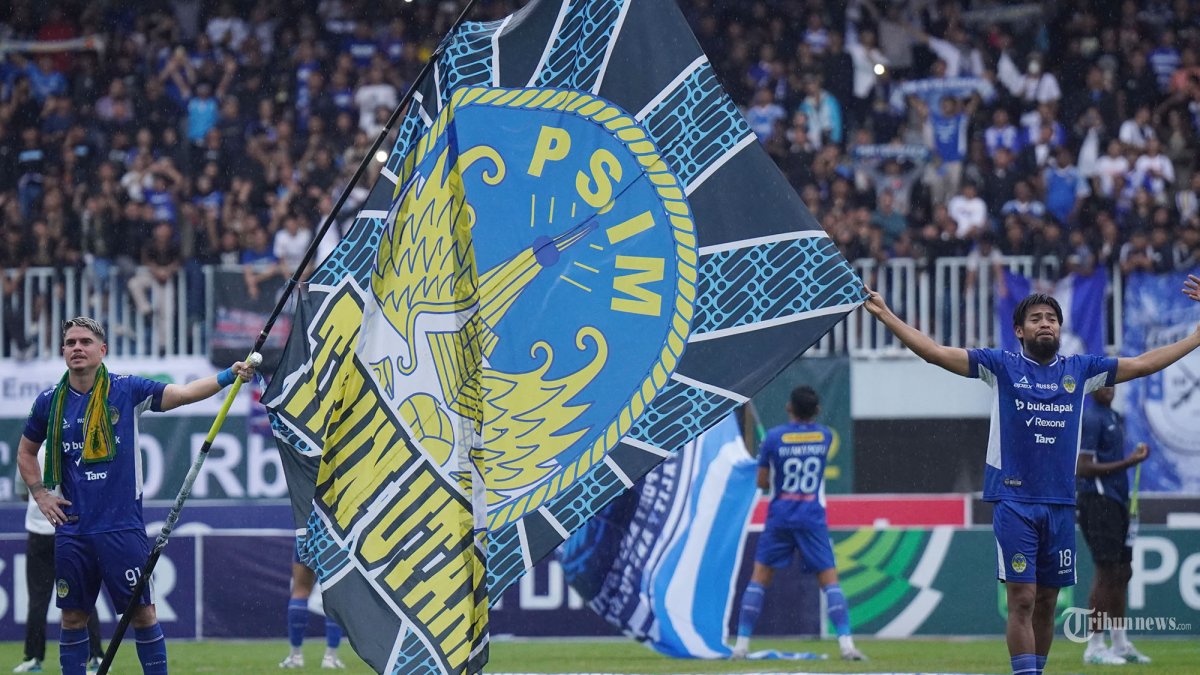 SELEBRASI - Pesepak bola PSIM Yogyakarta, Rafael Rodrigues (kiri) memegang bendera tim, bersama rekannya, Saldi setelah pertandingan melawan PSPS Riau Liga 2 2024/2025 babak 8 besar di Stadion Mandala Krida, Yogyakarta, Senin (17/2/2025) sore. PSIM berhasil mengalahkan PSPS 2-1 sekaligus memastikan tiket promosi Liga 1 2025/2026. Tribun Solo/Muhammad Nursina