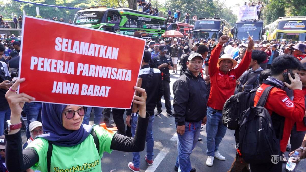 Pelaku usaha pariwisata menggelar aksi unjuk rasa di depan Gedung Sate, Jalan Diponegoro, Kota Bandung, Jawa Barat, Senin (21/7/2025). Aksi diikuti sekitar seribuan pelaku usaha pariwisata dengan memblokade lokasi aksi dengan memarkirkan ratusan bus pariwisata yang datang dari sejumlah daerah di Jawa Barat. Massa aksi sempat melakukan pelemparan botol air mineral dan berusaha mendobrak pintu gerbang Gedung Sate karena tidak bisa bertemu dengan Gubernur Jawa Barat, Dedi Mulyadi. Dalam aksinya, mereka mendesak Gubernur Jawa Barat mencabut Surat Edaran (SE) nomor 45/PK.03.03.KESRA tentang larangan menggelar studi tour. (TRIBUN JABAR/GANI KURNIAWAN)