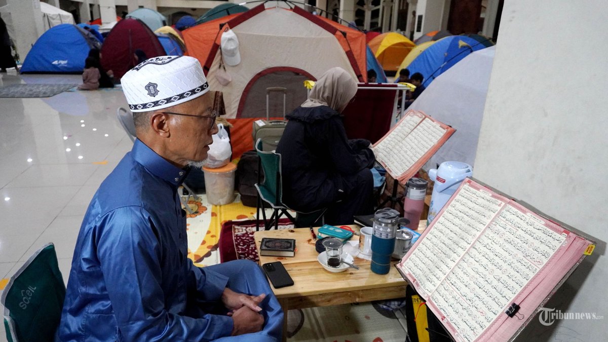 ITIKAF - Umat Islam membaca Alquran di depan tendanya saat mengikuti itikaf di Masjid Habiburrahman PT Dirgantara Indonesia (PT DI), Jalan Pajajaran, Kota Bandung, Jawa Barat, Jumat (21/3/2025). Pelaksanaan itikaf pada sepuluh hari terakhir Ramadan 1446 H di Masjid Habiburrahman diikuti sekitar 1.500 jemaah yang datang dari berbagai daerah di Jawa Barat dan Jakarta. Kebanyakan dari mereka datang bersama keluarga dan memilih mendirikan tenda di pelataran dan lantai dua masjid yang jumlahnya mencapai lebih dari 500 tenda. Selama itikaf para jemaah melaksanakan salat tarawih berjamaah dengan surat 1 juz Alquran setiap malam, qiamulail dengan surat 2 hingga 3 juz Alquran setiap malam, ceramah setelah salat isya, dan  kajian kitab Riyadush Sholihin setelah salat subuh. Sementara itu, guna memenuhi kebutuhan berbuka, sahur dan yang lainnya dari para peserta itikaf, DKM Masjid Habiburrahman pun menggandeng sekitar 50 UMKM untuk menjajakan dagangannya selama itikaf berlangsung. (TRIBUN JABAR/GANI KURNIAWAN)