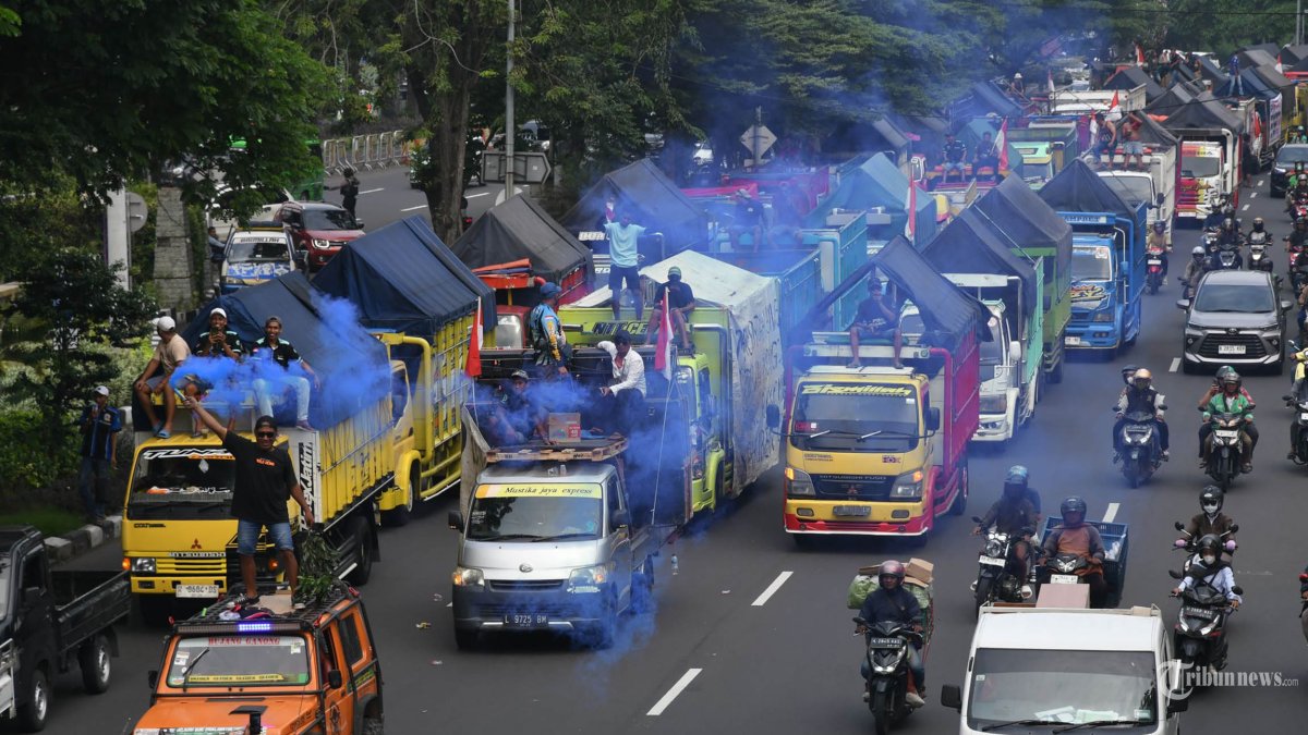 DEMO SOPIR TRUK - Massa demonstran mengatasnamakan diri sebagai Gerakan Sopir Jawa Timur (GSJT) berdatangan memasuki kota Surabaya melalui Bundaran Waru dan Jl A Yani Surabaya, Kamis (19/6/2025). Aksi long march dengan membentangkan kain merah dan putih sepanjang 1 Km ini melibatkan 785 truk, bertujuan menyuarakan berbagai macam aspirasi seluruh kalangan sopir truk dari 84 elemen yang tersebar se-Jatim. (SURYA/HABIBUR ROHMAN)