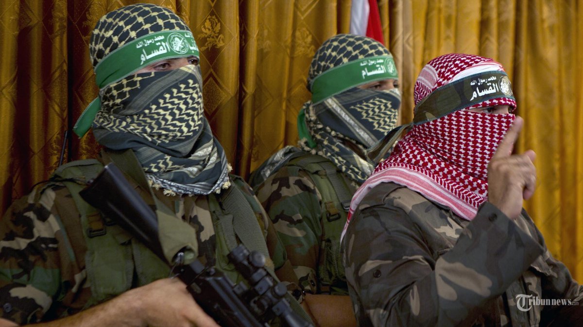 Abu Obeida (kanan), juru bicara resmi kelompok militan Palestina brigade Ezzedine al-Qassam, sayap bersenjata Hamas, memberikan konferensi pers di Kota Gaza.  (MOHAMMED ABED / AFP)