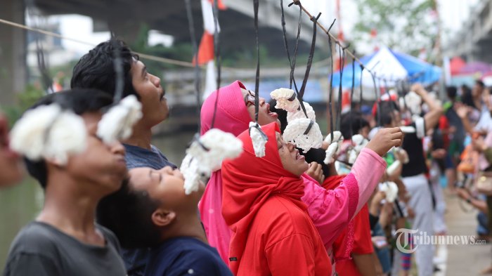 Sejumlah warga saat mengikuti lomba makan kerupuk di kawasan Cipinang Melayu, Kalimalang, Jakarta Timur, Sabtu (27/8/2022). Terlihat warga antusias mengikuti lomba makan kerupuk sepanjang 200 meter yang diikuti anak-anak hingga orang dewasa. Tribunnews/Jeprima