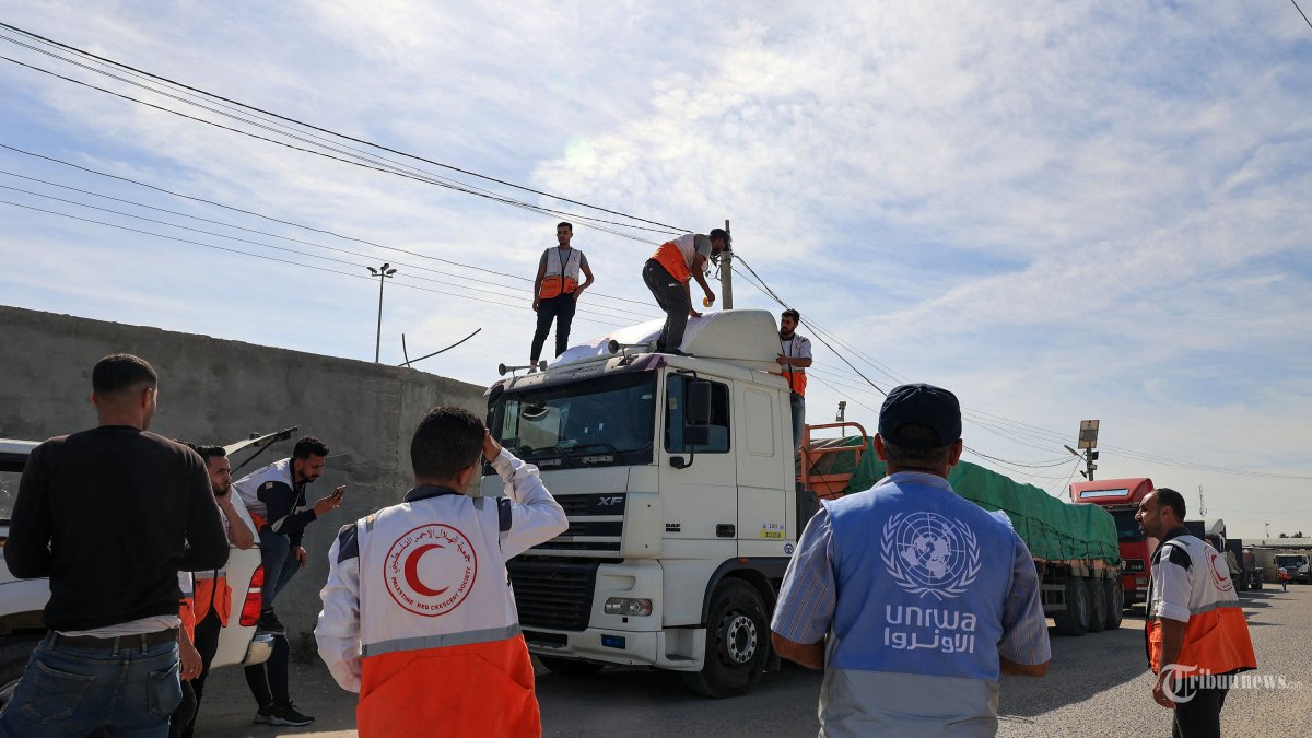 Pekerja bantuan berkumpul di sekitar truk yang membawa bantuan kemanusiaan yang memasuki Jalur Gaza dari Mesir melalui perbatasan Rafah pada 21 Oktober 2023. Truk pertama dari 20 truk yang membawa bantuan kemanusiaan memasuki Jalur Gaza yang dilanda perang dan terkepung pada 21 Oktober melalui perbatasan Rafah menyeberang dengan Mesir, kata koresponden AFP di kedua sisi. (Photo by SAID KHATIB / AFP)