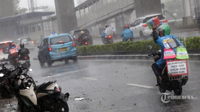 Pedagang jas hujan menawarkan jas hujan dengan motor ditengah hujan deras yang menguyur Jalan rasuna Said Kuningan, Jakarta Selatan, Kamis (23/12/2021). (Warta Kota/Henry Lopulalan)
