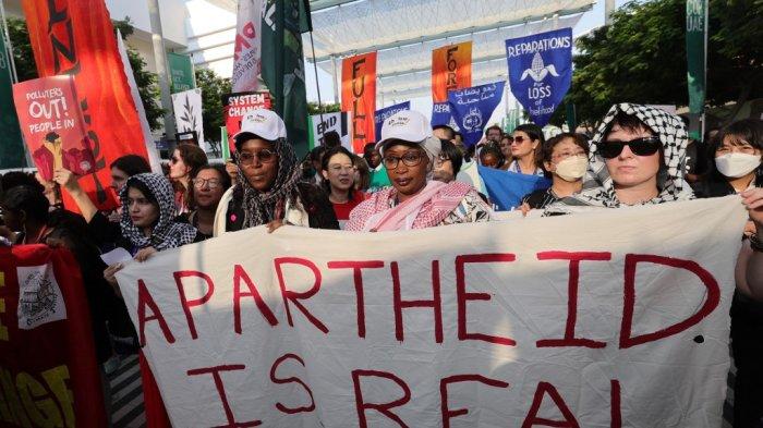 Aktivis iklim mengibarkan spanduk dan warna bendera Israel, selama pawai bersama 'keadilan iklim' dan 'gencatan senjata sekarang', menuntut diakhirinya kekerasan di Jalur Gaza, pada pertemuan puncak iklim PBB di Dubai, Uni Emirat Arab, pada 9 Desember 2023.