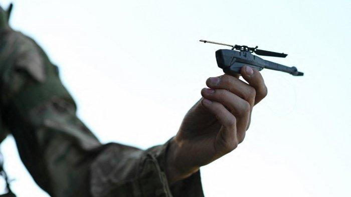 Perdana Menteri Inggris Boris Johnson (tidak digambarkan) diperlihatkan drone nano Black Hornet (kanan) selama pertemuan dengan personel militer di area pelatihan dataran Salisbury dekat Salisbury, barat daya Inggris pada 19 September 2019. Ben STANSALL / AFP / POOL