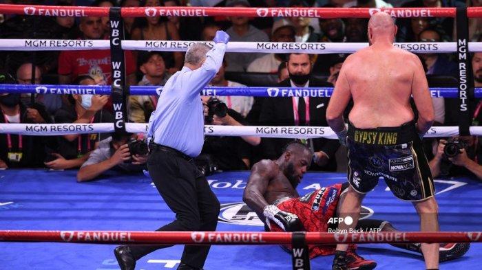 Penantang AS Deontay Wilder dijatuhkan oleh juara kelas berat WBC Tyson Fury dari Inggris Raya (kanan) saat mereka memperebutkan gelar kelas berat WBC/Lineal di T-Mobile Arena di Las Vegas, Nevada, 9 Oktober 2021.