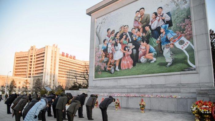 Orang-orang membungkuk untuk memberikan penghormatan di depan sebuah mozaik yang menunjukkan gambaran Presiden Kim Il Sung dan Kim Jong Il, untuk menandai peringatan sepuluh tahun kematian Kim Jong Il, ayah dari pemimpin saat ini Kim Jong Un, di Pyongyang pada 17 Desember 2021. KIM Won Jin / AFP