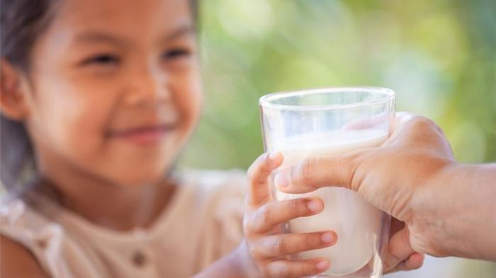 ilustrasi memberikan susu pertumbuhan sebagai pelengkap nutrisi anak.