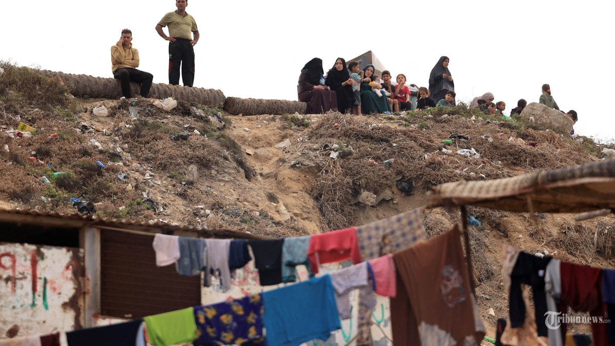 Binatu yang dicuci menggunakan air laut karena kekurangan air bersih dan listrik, digantung di depan gubuk di sepanjang pantai di Deir el-Balah di selatan Jalur Gaza pada 29 Oktober 2023, di tengah pertempuran yang sedang berlangsung antara Israel dan kelompok Palestina Hamas. Israel menggempur Gaza yang dikuasai Hamas pada tanggal 29 Oktober, dalam serangan udara dan darat yang meningkat ketika PBB memperingatkan bahwa ketertiban sipil ?mulai rusak? di wilayah Palestina yang terkepung. Ribuan warga sipil, baik warga Palestina maupun Israel, telah tewas sejak 7 Oktober 2023, setelah militan Hamas Palestina yang berbasis di Jalur Gaza memasuki Israel selatan dalam serangan yang belum pernah terjadi sebelumnya yang memicu perang yang diumumkan oleh Israel terhadap Hamas dengan pemboman balasan di Gaza. (Photo by MAHMUD HAMS / AFP)