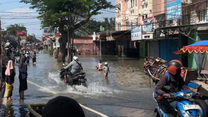 BANJIR - Motor listrik atau Electric Vehicle (EV) tidak gentar menerjang banjir di Jalan Raya Cipondoh, Selasa (8/7/2025)/ Danang Triatmojo