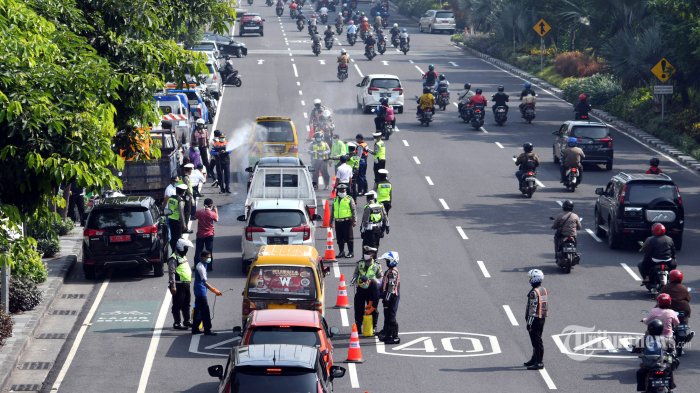 JALAN DI SURABAYA - Petugas dari Dishub dan Polrestabes Surabaya melakukan penyemprotan disinfektan pada kendaraan roda empat di frontage road Jalan A Yani yang merupakan salah satu pintu masuk ke Kota Surabaya, Jawa Timur, Jumat (27/3/2020). Penyemprotan disinfektan tersebut merupakan salah satu cara Pemkot Surabaya mencegah penyebaran virus corona (Covid-19).