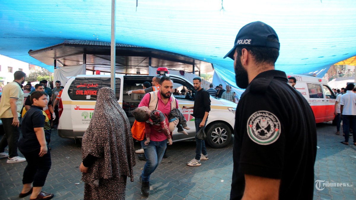 Seorang pria menggendong seorang anak saat dia bergegas ke rumah sakit Al-Shifa menyusul pemboman Israel di lingkungan Mansura Kota Gaza, di pinggiran timur Shujaiya pada 4 November 2023, di tengah pertempuran yang sedang berlangsung antara Israel dan kelompok Palestina Hamas. Ribuan warga sipil, baik warga Palestina maupun Israel, telah tewas sejak 7 Oktober 2023, setelah militan Hamas Palestina yang berbasis di Jalur Gaza memasuki Israel selatan dalam serangan yang belum pernah terjadi sebelumnya yang memicu perang yang diumumkan oleh Israel terhadap Hamas dengan pemboman balasan di Gaza. (Photo by Bashar TALEB / AFP)