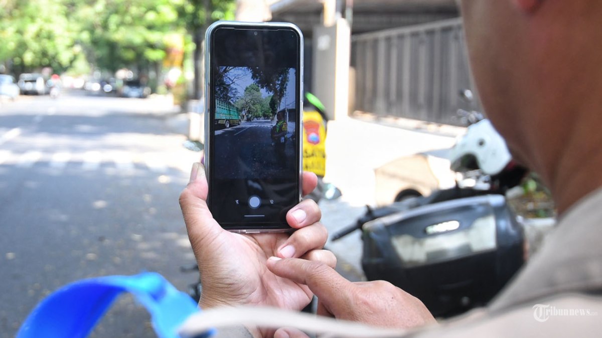 Anggota Satuan Lalu Lintas (Satlantas) Polresta Malang Kota melakukan penindakan menggunakan Smartphone ETLE Mobile Handheld (EMH) usai di launching di Polresta Malang Kota, Jawa Timur, Rabu (24/7/2024). Polresta Malang Kota meluncurkan dua unit smartphone ETLE Mobile Handheld (EMH) yakni perangkat genggam berbasis teknologi informasi yang digunakan sebagai alat penegakkan hukum terhadap pelanggaran lalu lintas. SURYA/PURWANTO