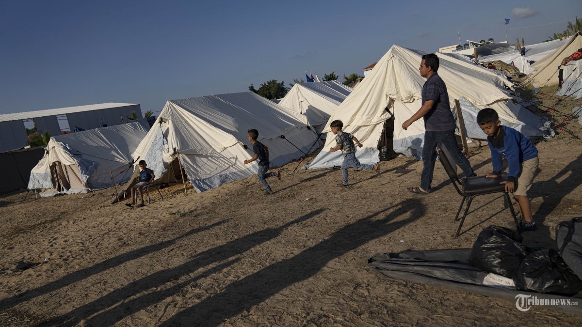 Warga Palestina yang mengungsi akibat pemboman Israel di Jalur Gaza berjalan di kamp tenda yang disediakan UNDP di Khan Younis pada Kamis, 19 Oktober 2023. Ratusan warga Palestina berkerumun di kamp tenda kumuh di Gaza selatan, sebuah gambaran yang membawa kembali kenangan akan trauma terbesar mereka. Pembangunan kota tenda yang dilakukan secara dadakan di Khan Younis untuk melindungi sejumlah warga Palestina yang kehilangan atau meninggalkan rumah mereka selama beberapa hari terakhir akibat pemboman hebat Israel telah menimbulkan kemarahan, ketidakpercayaan dan kesedihan di seluruh dunia Arab. (AP Photo/Fatima Shbair, File)