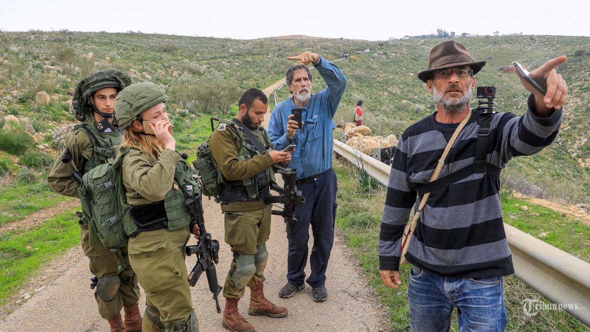 Aktivis Israel Guy Hirschfeld (kanan) dan Rabbi Arik Ascherman (kedua-kanan) berdebat dengan tentara Israel setelah mereka meminta para penggembala Palestina untuk meninggalkan daerah yang ditetapkan sebagai zona militer di kota Um Zuka, sebelah utara Lembah Jordan, pada 19 Februari 2020. Hirschfeld dan Ascherman adalah aktivis Israel yang bekerja menentang pengambilalihan Lembah Yordan, bagian penting dari Tepi Barat yang diduduki oleh negara mereka, yang dianggap penting oleh Palestina untuk masa depan negara mereka. (Emmanuel DUNAND/AFP)