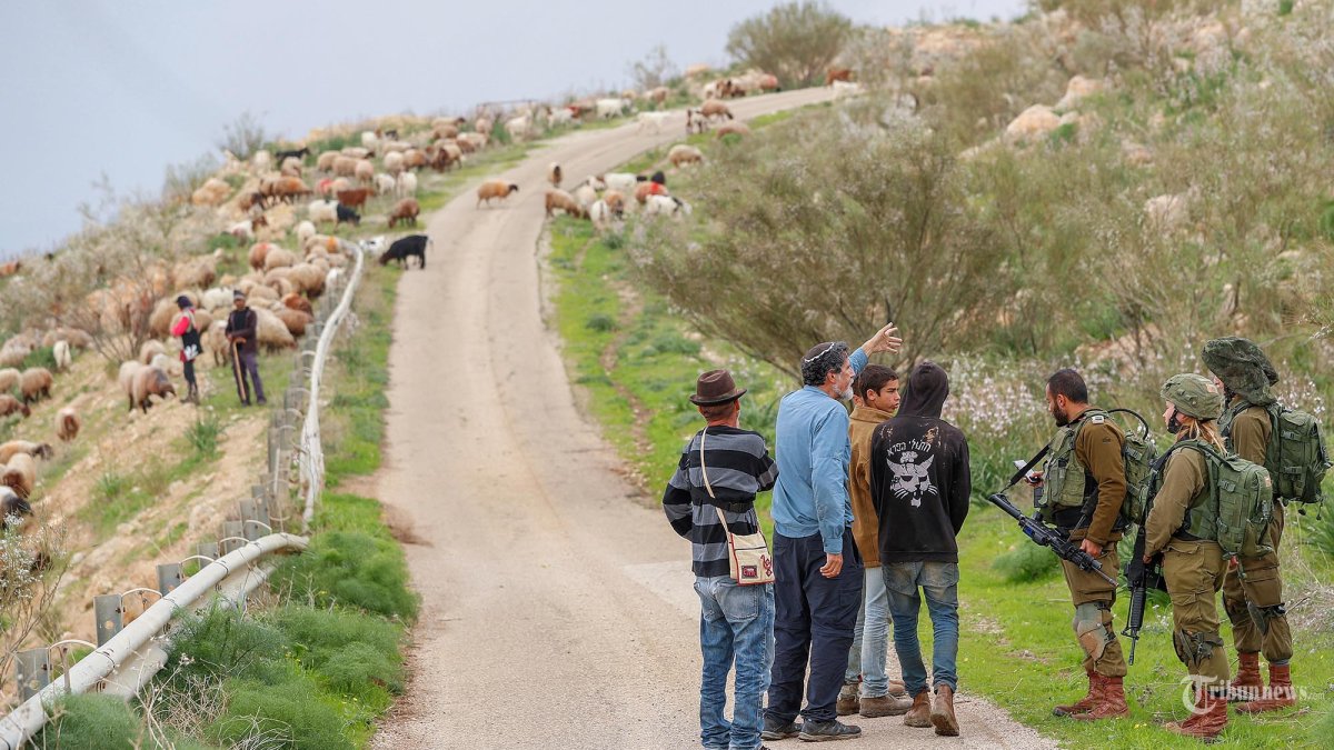 Aktivis Israel Guy Hirschfeld (kiri) dan Rabbi Arik Ascherman (tengah) menghadapi pemukim muda Israel setelah mereka mengusir para penggembala Palestina (latar belakang), di area yang ditetapkan sebagai zona militer di kota Um Zuka, sebelah utara Lembah Jordan, pada 19 Februari. 2020. Hirschfeld dan Ascherman adalah aktivis Israel yang menentang pengambilalihan Lembah Yordan yang dilakukan negara mereka, bagian penting dari Tepi Barat yang diduduki yang dianggap penting oleh Palestina untuk masa depan negara mereka. (Emmanuel DUNAND/AFP)