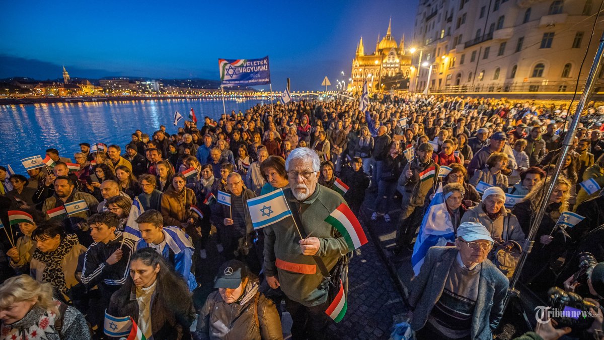 Demonstran Hongaria mengibarkan bendera Hongaria dan Israel saat unjuk rasa mendukung Israel di tepi sungai Danube di Budapest, Hongaria, pada 10 Oktober 2023. Pertempuran antara Israel dan Hamas telah memasuki hari keempat setelah serangan besar-besaran dari Gaza oleh kelompok militan Palestina pada tanggal 7 Oktober, dan jumlah korban tewas meningkat di kedua pihak. (Photo by FERENC ISZA / AFP)