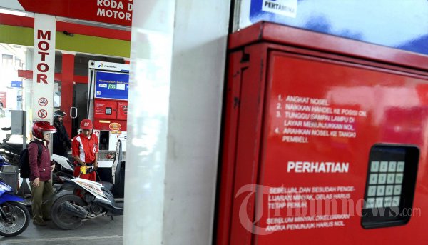 Seorang petugas pompa bensin di stasiun pengisian bahan bakar yang ramai