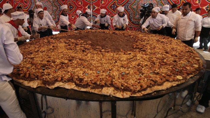 Koki Palestina memberikan sentuhan akhir pada sajian besar Musakhan, hidangan tradisional Palestina yang terbuat dari ayam, roti pipih, kacang-kacangan, dan rempah-rempah, pada 19 April 2010 di desa Arura, Tepi Barat, dekat Ramallah. Perdana Menteri Palestina Salam Fayyad menghadiri acara tersebut. FOTO AFP/ABBAS MOMANI