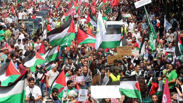 Orang-orang mengibarkan bendera Palestina saat demonstrasi menentang operasi militer Israel di Gaza di Brussels pada 27 Juli 2014. Israel pada 27 Juli melanjutkan serangan militernya di Gaza setelah tembakan roket yang 