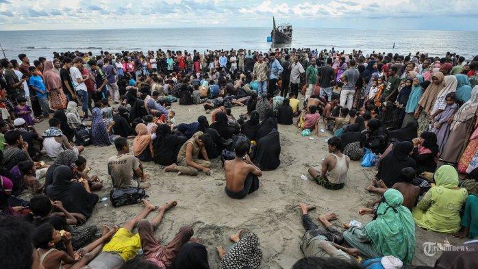 Pengungsi Rohingya yang baru tiba beristirahat di pantai setelah masyarakat setempat memutuskan untuk mengizinkan mereka sementara mendarat untuk mendapatkan air dan makanan di Ulee Madon, provinsi Aceh, Indonesia, pada 16 November 2023. Sekitar 250 pengungsi Rohingya mencapai Indonesia bagian barat dengan perahu kayu yang penuh sesak pada 16 November 2023, sehingga jumlah pengungsi yang dilaporkan oleh pejabat setempat tiba pada minggu ini menjadi hampir 600 orang. (Photo by AMANDA JUFRIAN / AFP)