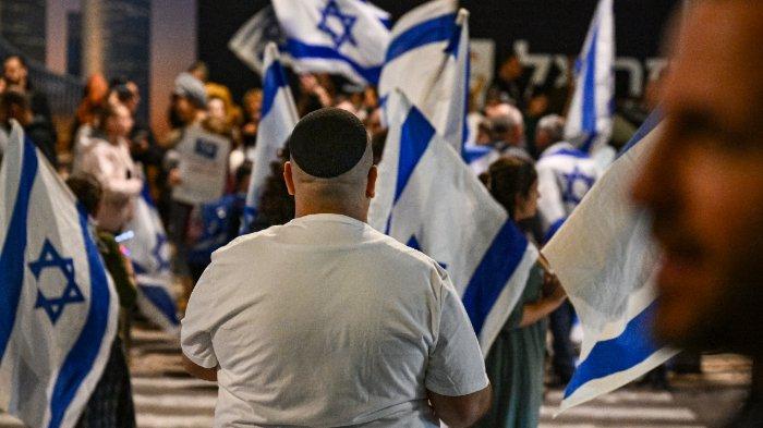 Pengunjuk rasa sayap kanan Israel berdemonstrasi di dekat Kementerian Pertahanan di Tel Aviv pada 16 Desember 2023, dekat dengan demonstrasi lain yang dilakukan teman dan kerabat sandera Israel yang ditahan di Gaza sejak serangan 7 Oktober.