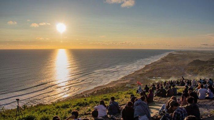 Wisatawan sedang menikmati matahari terbenam atau sunset di Bukit Paralayang Watu Gupit, Yogyakarta.