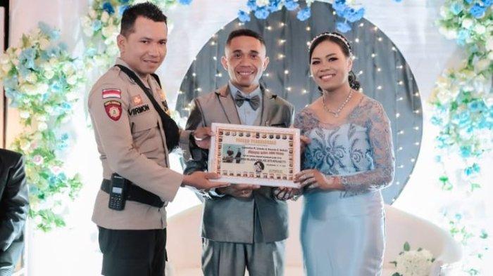 Brigadir Polisi Kepala (Bripka) M Virmon, saat memberikan piagam penghargaan kepada pengantin di Kelurahan Kefa Utara, Kabupaten Timor Tengah Utara, NTT