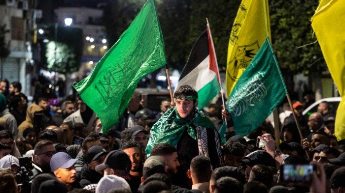Seorang tahanan Palestina (tengah) memberi isyarat di antara para pendukung dan kerabatnya setelah dibebaskan dari penjara Israel dengan imbalan sandera Israel yang dibebaskan oleh Hamas dari Jalur Gaza, di Ramallah di Tepi Barat yang diduduki pada 26 November 2023. Layanan penjara Israel mengatakan 39 tahanan Palestina dibebaskan pada 26 November 2023 berdasarkan ketentuan perjanjian gencatan senjata antara Israel dan Hamas di Jalur Gaza. Pengumuman itu muncul setelah 13 sandera Israel dibebaskan di wilayah Palestina berdasarkan kesepakatan tersebut, bersama dengan tiga warga Thailand dan seorang warga negara ganda Rusia-Israel.