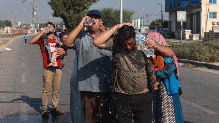 Orang-orang minum air setelah mencapai Jalur Gaza tengah dengan berjalan kaki melalui jalan Salah al-Din dalam perjalanan ke bagian selatan daerah kantong Palestina pada 5 November 2023. Selebaran yang dijatuhkan oleh tentara Israel pada 5 November mendesak warga Kota Gaza untuk mengungsi ke selatan antara pukul 10 pagi (0800 GMT) dan 14:00 (1200 GMT), sehari setelah seorang pejabat AS mengatakan setidaknya 350.000 warga sipil masih berada di dalam dan sekitar kota yang sekarang menjadi zona perang perkotaan.