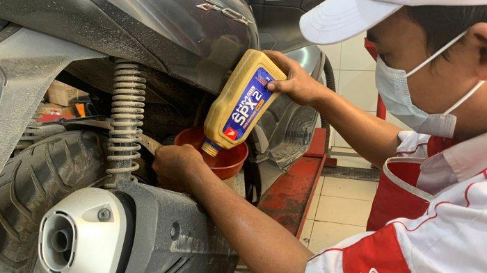 Mekanik AHASS melakukan penggantian oli sepeda motor Honda menggunakan AHM OIL kemasan terbaru.