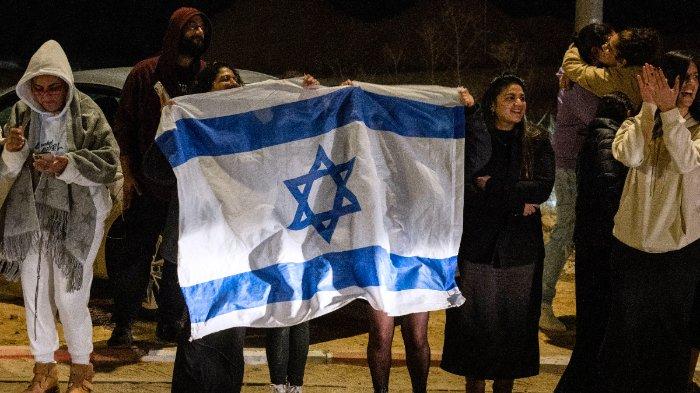 Para pendukung mengibarkan bendera saat kedatangan sandera Israel yang baru saja dibebaskan, di luar pangkalan militer Ofakim di Israel selatan pada awal 1 Desember 2023, setelah dibebaskan dari Jalur Gaza