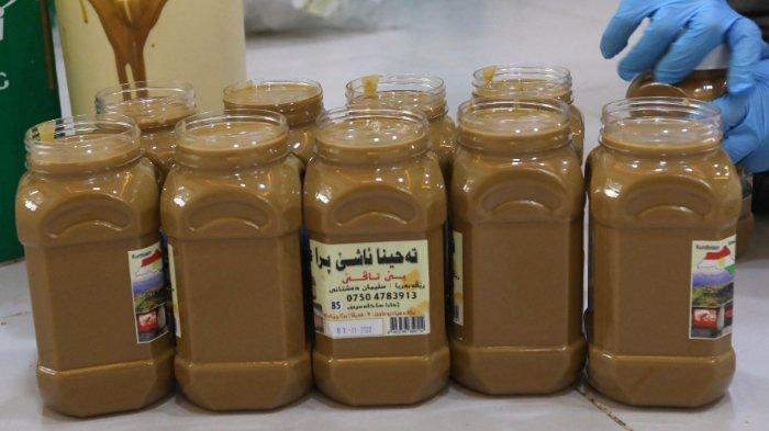 Seorang pria Kurdi Irak mengisi wadah plastik dengan tahini segar (tahina), bumbu yang terbuat dari biji wijen, di distrik Amadiyah di wilayah otonomi Kurdistan Irak, pada 21 November 2020.