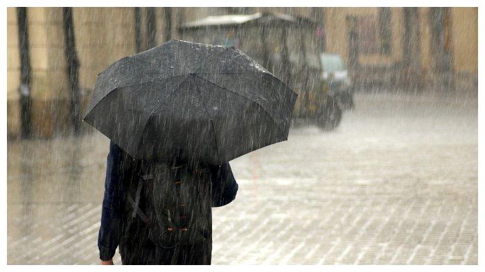Ilustrasi seseorang memakai payung di tengah hujan. Kapan Musim Hujan di Indonesia Tahun 2024 ? Begini Kata BMKG