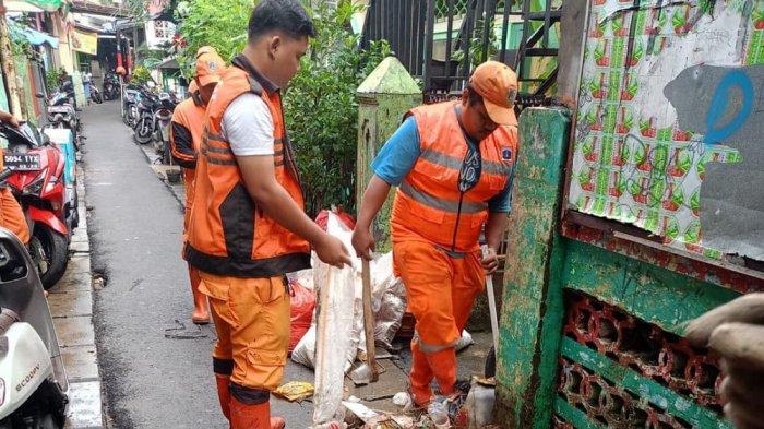 BERSIHKAN LUMPUR - Petugas Penanganan Prasarana dan Sarana Umum (PPSU) berjibaku membersihkan lingkungan warga pascabanjir di RW 04, Kecamatan Jatinegara, Jakarta Timur, Selasa (8/7/2025). 