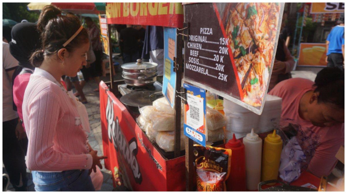 Seorang pembeli hendak melakukan pembayaran nontunai di Kedai Jenny Burger dan Pizza Meyla yang berlokasi di Jalan Slamet Riyadi, Solo.
