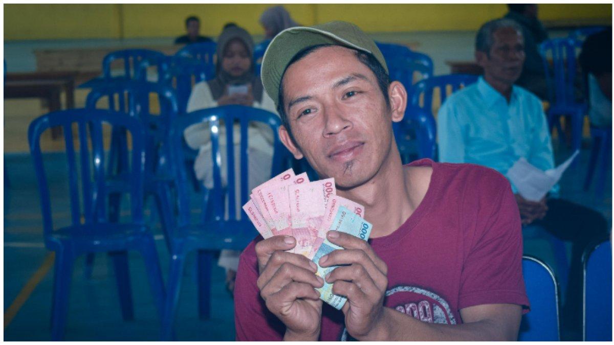 Seorang warga desa memamerkan THR Lebaran yang diberikan BUMDes Sriwulan Makmur.
