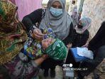 Petugas-Kesehatan-Tengah-Memberikan-Vaksin-Polio-Kepada-Seorang-Anak-di-Timur-Tengah.jpg